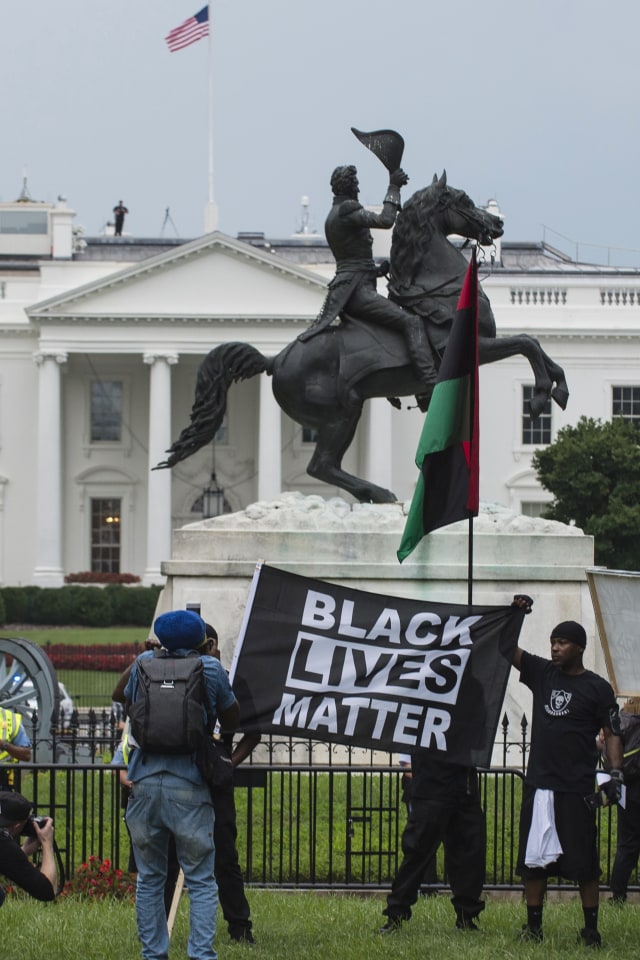 Demonstran memegang bendera bertuliskan 'Black Lives Matter' saat aksi protes di depan Gedung Putih, Washington, Amerika Serikat pada 12 Agustus 2018. Foto: AFP/ Eric BARADAT