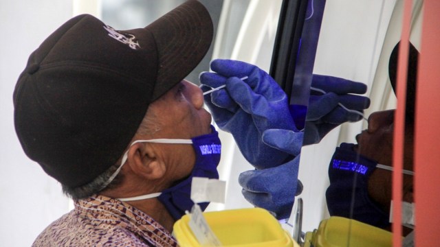 Warga mengikuti test swab COVID-19 menggunakan mobil tes polymerase chain reaction (PCR) atau Mobile Combat COVID-19 di RSUD Sidoarjo, Jawa Timur, Kamis (28/5). Foto: ANTARA FOTO/Umarul Faruq