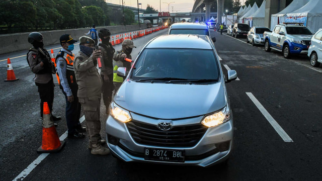 Petugas gabungan melakukan pemeriksaan terhadap pengguna kendaraan yang akan masuk ke wilayah DKI Jakarta di di KM 47 Tol Cikampek-Jakarta, Jawa Barat. Foto: ANTARA FOTO/Muhammad Adimaja