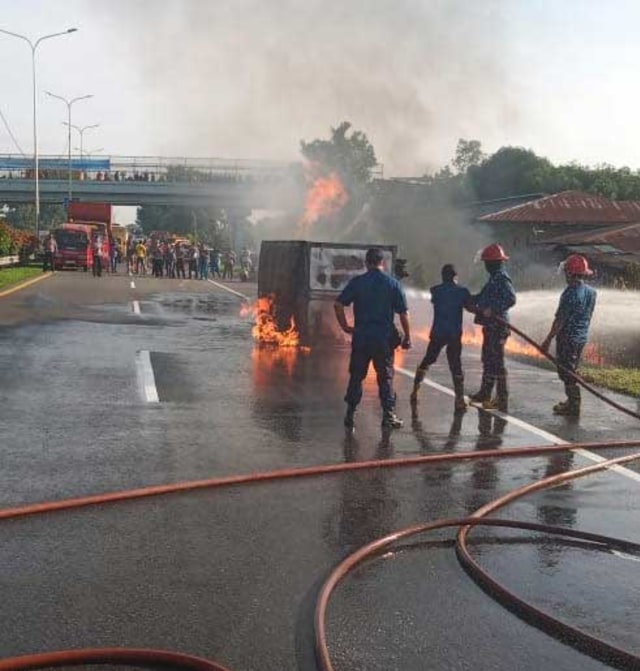 Petugas pemadam kebakaran memadamkan api di mobil yang terbakar. Foto: Istimewa