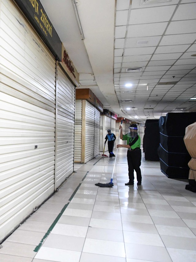 Petugas terlihat membersihkan pusat perbelanjaan Thamrin City, Jakarta yang belum beroperasi. Foto: ANTARA FOTO/Hafidz Mubarak A