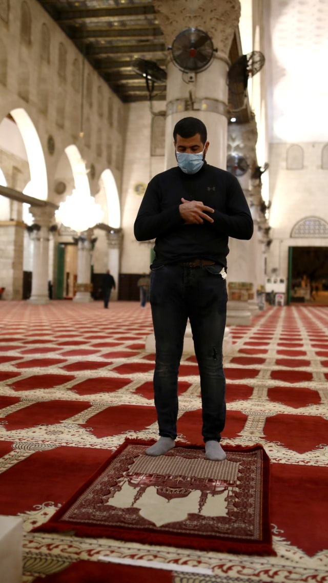 Seorang pria yang mengenakan masker saat salat di masjid Al-Aqsa, Kota Tua Yerusalem, Minggu (31/5). Foto: REUTERS/Ammar Awad