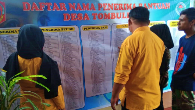 Warga melihat langsung daftar nama-nama penerima bantuan yang dipajang oleh aparat desa di kantor desa. Minggu, (31/5). Foto: Dok istimewa