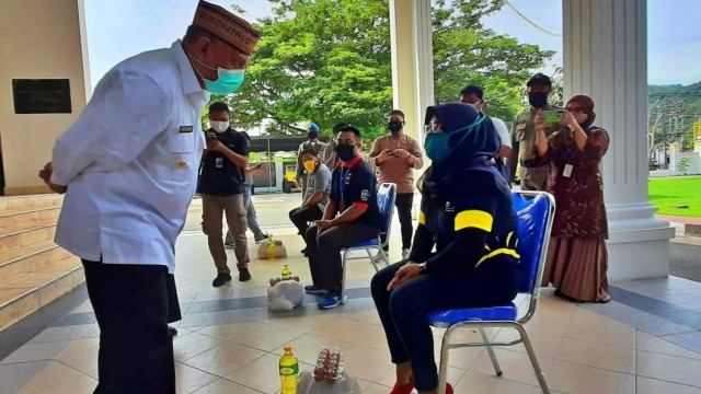 Gubernur Gorontalo, Rusli Habibie, saat memberikan bantuan secara simbolis kepada salah seorang warga. Senin, (1/6). Foto: Dok banthayo.id (Wawan Akuba)