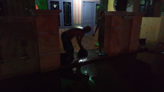 Warga Prapag Kidul mengatasi air rob yang masuk rumah.