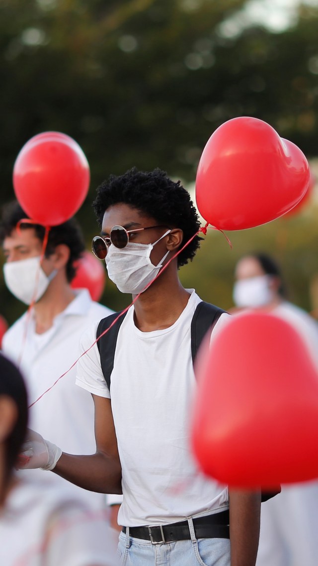 Sejumlah seniman tampil dengan balon merah berbentuk hati untuk menghormati korban meninggal akibat COVID-19 di Brasilia, Brasil, Senin (1/6). Foto: Reuters/Adriano Machado
