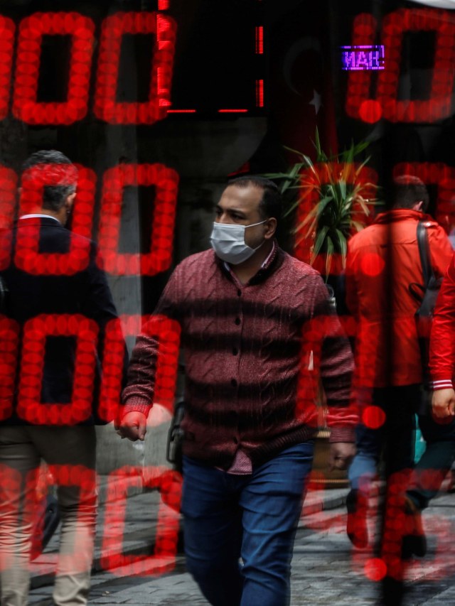 Seseorang mengenakan masker terlihat di cermin toko penukaran mata uang asing di Grand Bazaar abad ke-15, Turki. Foto: AP Photo/Emrah Gurel