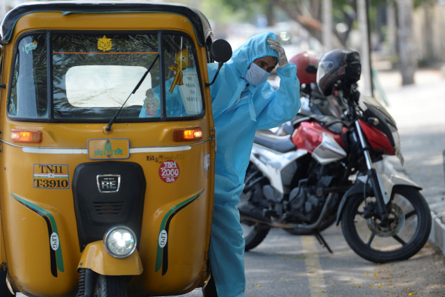Seorang pengemudi bajaj menggunakan alat pelindung diri usai membawa penumpang di Chennai, India. Foto: AFP/Arun SANKAR