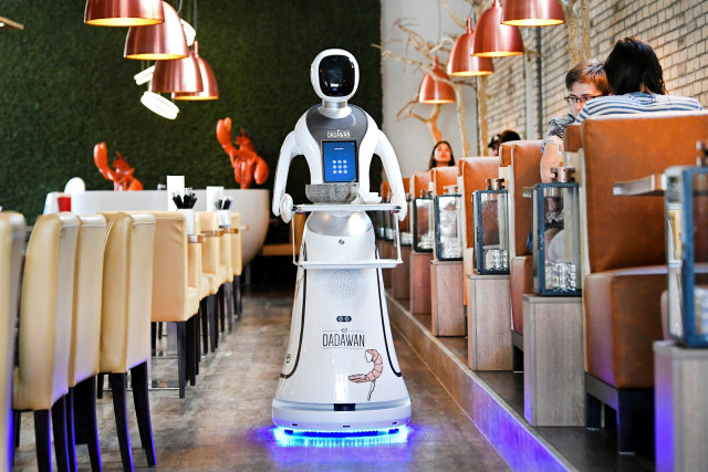 Sebuah robot melayani pengunjung untuk mengurangi penyebaran virus corona di sebuah restoran China di Maastricht, Belanda. Foto: REUTERS / Piroschka van de Wouw