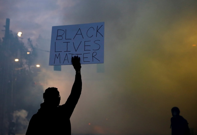 Seorang demonstran memegang papan bertuliskan Black Lives Matter' saat aksi demo berlangsung di Seattle, Washington, AS, Senin (1/6). Foto:  REUTERS/Lindsey Wasson