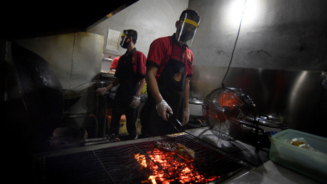 Karyawan mengenakan pelindung wajah (face shield) saat mempersiapkan pesanan makanan di salah satu Restoran di Jakarta.  Foto: ANTARA FOTO/Puspa Perwitasari