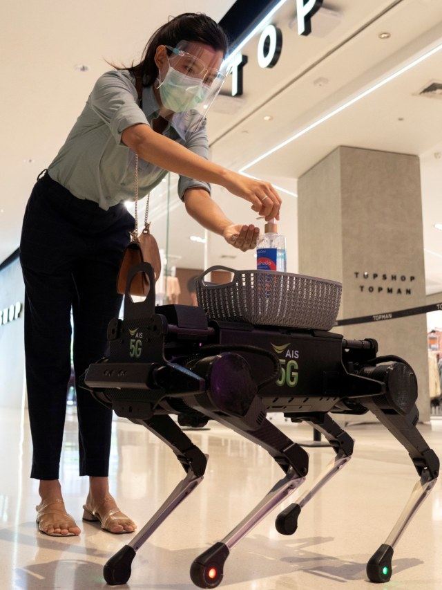 Robot 5G K9 mendistribusikan hand sanitizer kepada pengunjung di pusat perbelanjaan di Bangkok, Thailand. Foto: REUTERS/Athit Perawongmetha