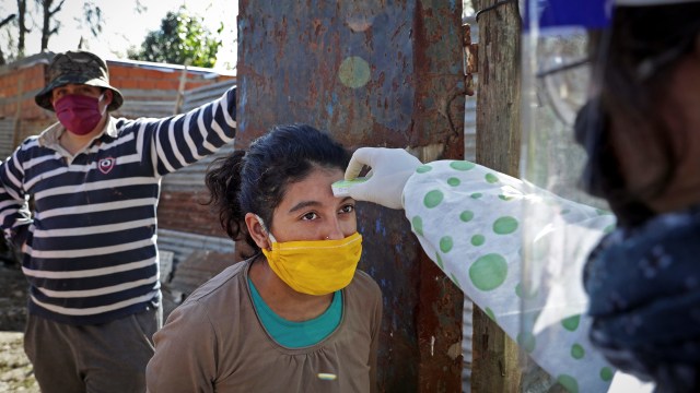 Petugas medis memeriksa suhu tubuh seorang warga di Altos de San Lorenzo, La Plata, Argentina. Foto: AFP/ALEJANDRO PAGNI