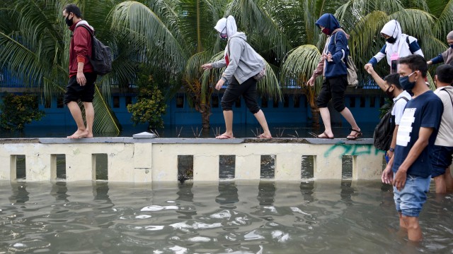 Warga melintasi banjir air rob di kawasan Muara Baru, Penjaringan, Jakarta Utara, Jumat (5/6).  Foto: ANTARA FOTO/M Risyal Hidayat