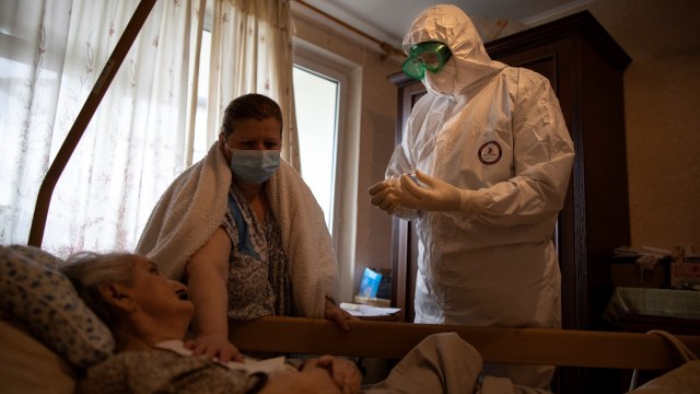Pastor Vasily Gelevan mengenakan pakaian hazmat saat memberikan komuni suci kepada seorang pasien diduga terinfeksi COVID-19, di Moskow, Rusia. Foto: Alexander Zemlianichenko/AP Photo