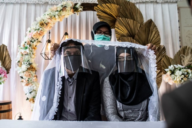 Calon pasangan pengantin mengenakan masker dan pelindung wajah saat prosesi akad nikah di KUA Ciracas, Jakarta, Sabtu (6/6). Foto: ANTARA FOTO/Aprillio Akbar
