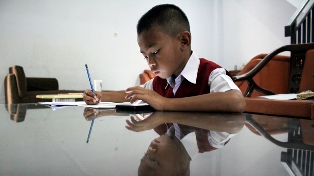 Seorang murid sekolah dasar mengerjakan soal Ujian Akhir Semester (UAS) Genap di rumahnya di Kota Makassar, Sulawesi Selatan, Senin (8/6/2020). Foto: ANTARA FOTO/Arnas Padda