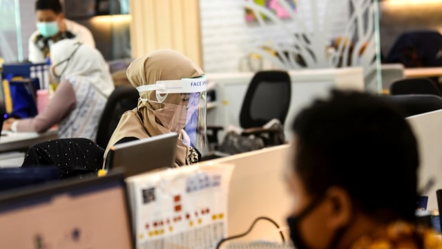 Karyawan menggunakan pelindung wajah saat melakukan aktivitas di pusat perkantoran, kawasan SCBD, Jakarta, Senin (8/6/2020). Foto: Muhammad Adimaja/ANTARA FOTO