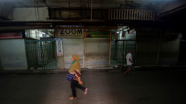 Warga melintasi kios-kios yang belum beroperasi di Pasar Senen Blok V, Jakarta. Foto: ANTARA FOTO/Aditya Pradana Putra