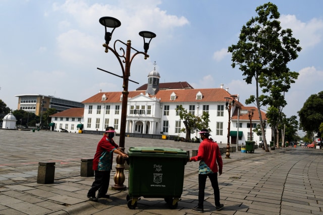 Petugas kebersihan beraktivitas di Kawasan Kota Tua, Jakarta, Sabtu (13/6). Foto: M Risyal Hidayat/ANTARA FOTO