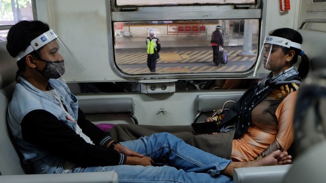 Penumpang memakai masker dan pelindung wajah (Face Shield)�di Kereta Api (KA) Ranggajati relasi Cirebon-Jember saat transit di Stasiun Balapan, Solo. Foto: ANTARA FOTO/Maulana Surya