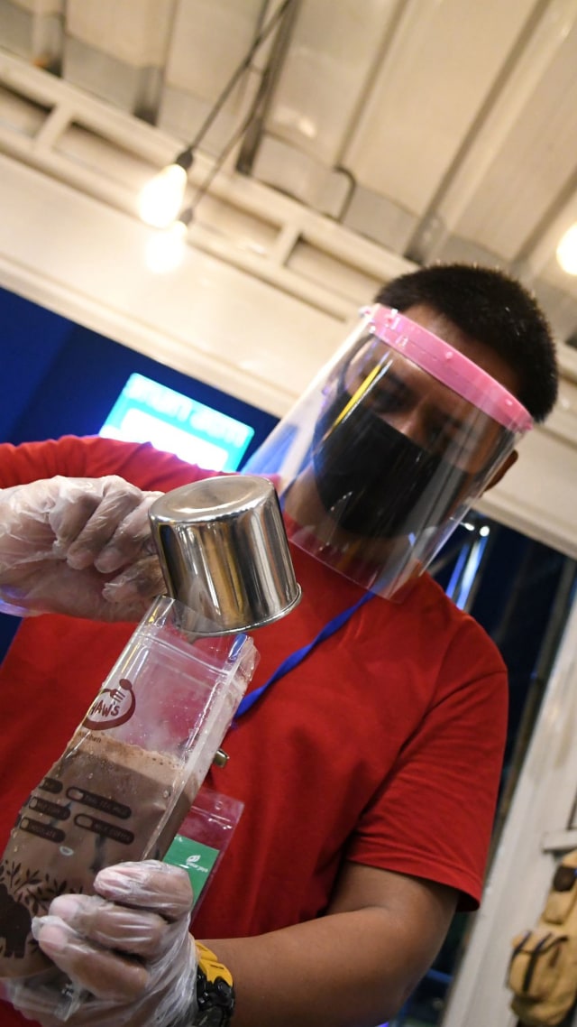 Seorang pedagang dengan mengenakan masker, pelindung wajah dan sarung tangan plastik meracik minuman saat pembukaan kembali pusat kuliner Thamrin 10. Foto:  ANTARA FOTO/M Risyal Hidayat
