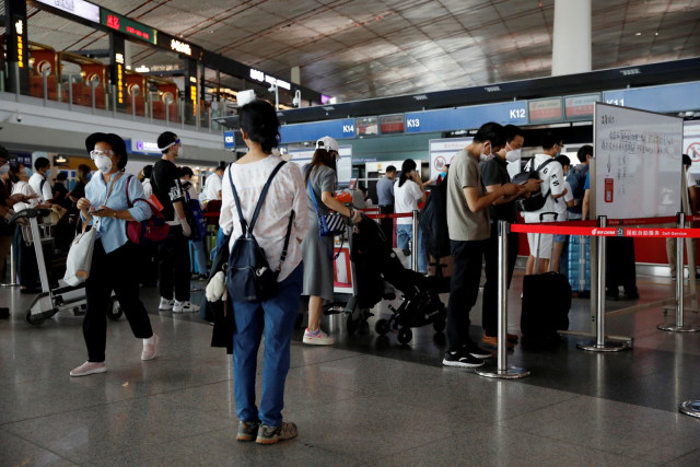 Sejumlah calon penumpang mengantre saat berada di Beijing Capital International Airport, China, Rabu (17/6). Foto: Carlos Garcia Rawlins/ REUTERS