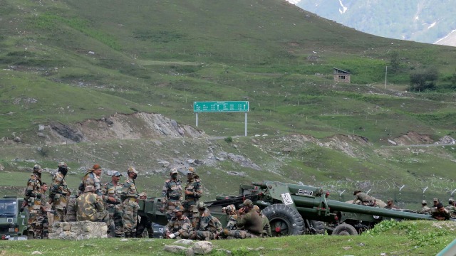 Prajurit tentara India beristirahat di sebelah senjata artileri di kamp transit sementara sebelum menuju ke Ladakah. Foto: Stringer/REUTERS