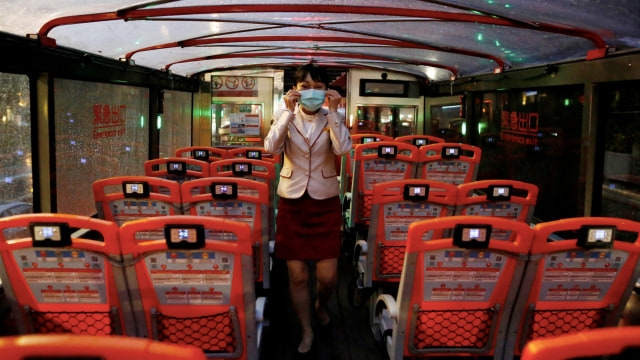 Seorang pemandu wisata menggunakan masker di dalam bus Taipei Sightseeing yang kosong di Taipei, Taiwan pada 22 Mei 2020. Foto: Ann Wang / REUTERS