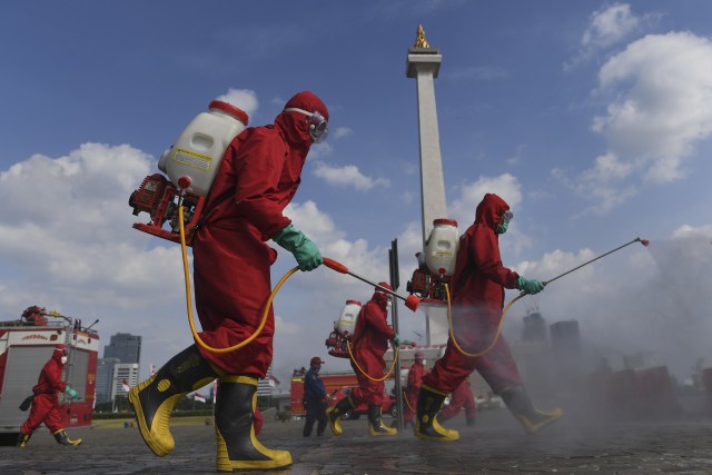 Petugas Pemadam Kebakaran menyemprotkan cairan disinfektan di kawasan Monumen Nasional (Monas), Jakarta, Rabu (17/6). Foto: Wahyu Putro A/Antara Foto
