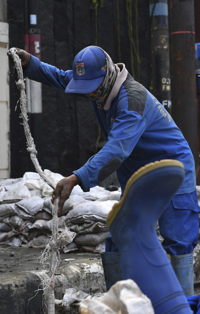 Petugas Dinas Sumber Daya Air DKI Jakarta mengambil sampah di gorong-gorong Jalan HOS Cokroaminoto, Jakarta, Jumat (19/6). Foto: Wahyu Putro A/Antara Foto