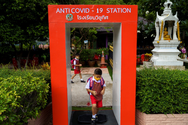 Siswa taman kanak-kanak sekolah Wichuthit memakai masker dan melewati stasiun anti-COVID-19 saat kembali sekolah di Bangkok, Thailand.  Foto: Athit Perawongmetha / REUTERS