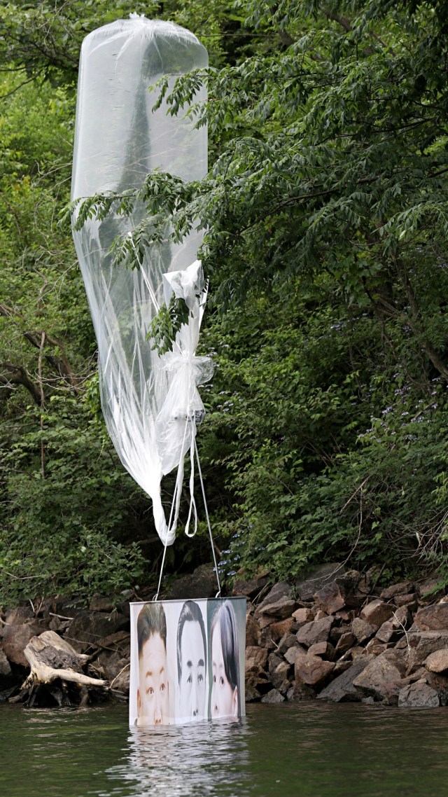 Balon udara dengan selebaran anti-Korea Utara yang dikirim kelompok pembelot mendarat di sungai sebuah bukit di Hongcheon, Korea Selatan, Selasa (23/6). Foto: Yonhap via Reuters