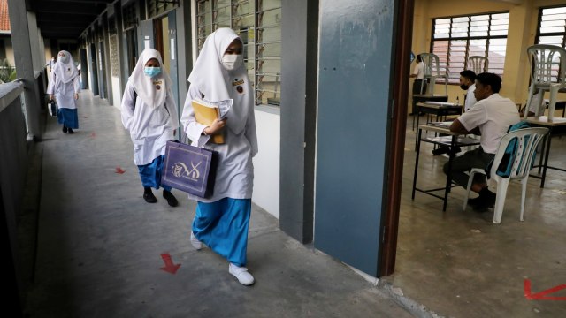 Pelajar yang mengenakan masker berjalan di lorong kelas pada salah satu  sekolah menengah di Shah Alam, Malaysia, Rabu (24/6). Foto: Lim Huey Teng/Reuters