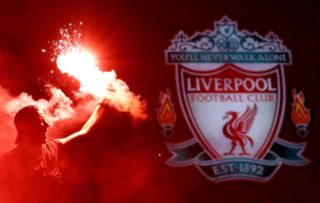 Salah satu suporter menyalakan flair di samping logo Liverpool saat  merayakan kemenangan Premier League di luar Anfield. Foto: Phil Noble/Reuters