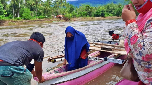 Aktifitas warga di dua kecamatan di Kabupaten Bone Bolango, Gorontalo, saat menaiki perahu kayu. Jumat, (26/6). Foto: Dok banthayoid (Fadhil Hadju)