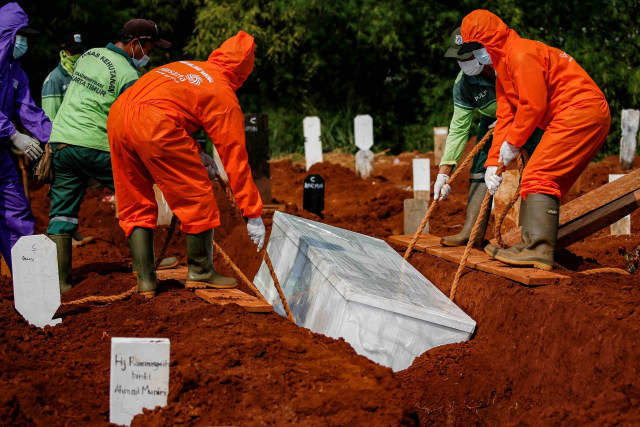 Petugas memasukan peti jenazah pasien virus corona di pemakaman Pondok Ranggon, Jakarta Timur. Foto: Willy Kurniawan/REUTERS