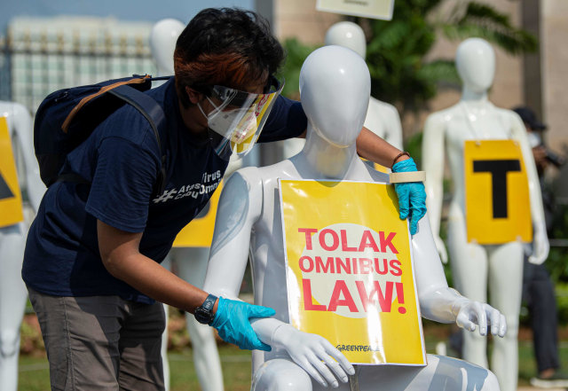 Aktivis Greenpeace memasang poster pada manekin saat aksi damai menolak pembahasan RUU Cipta Kerja di depan Kompleks Parlemen, Senayan, Jakarta. Foto: Aditya Pradana Putra/ANTARA FOTO