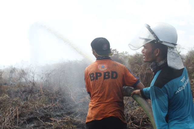 Petugas berupaya memadamkan api di lahan perkebunan yang terbakar di Aceh Barat. Foto: Dok. acehkini