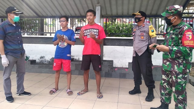 Pelda Yusuf, Babinsa Sememi dan Bhabinkamtibmas setempat memberikan sanksi terhadap para pemuda yang kedapatan tak mengenakan masker. Foto: Pendam TNI