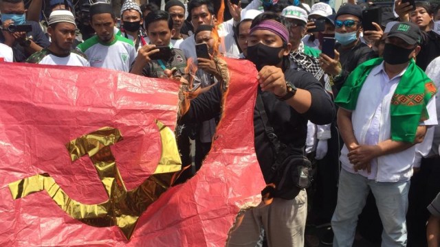 Massa yang demo menolak RUU HIP membakar bendera palu arit di depan Lapangan Merdeka, Medan, Sumatera Utara.  Foto: Rahmat Utomo/kumparan 