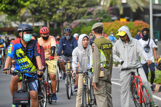 Petugas Satpol PP terlihat memberhentikan pesepeda yang tidak menggunakan masker. Foto: Nova Wahyudi/ANTARA FOTO