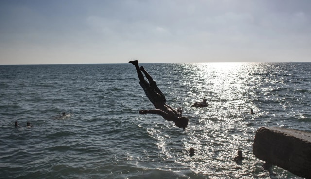 Sejumlah warga Palestina menghabiskan waktu musim panas dengan berenang di pantai. Foto: Khalil Amra/AP Photo