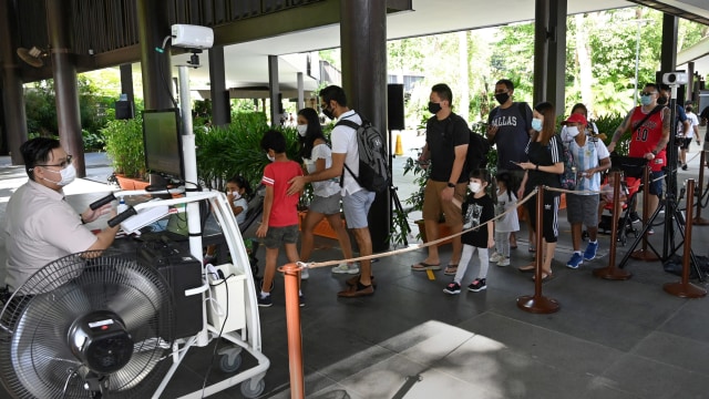 Pengunjuk diperiksa suhu tubuh saat akan masuk ke Kebun Binatang Singapura, Singapura, Senin (6/7). Foto: Roslan RAHMAN / AFP