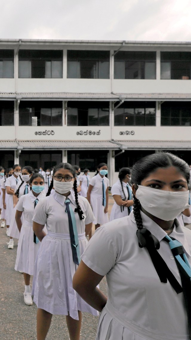 Para siswa yang mengenakan masker saat berbaris sebelum masuk ke kelas pada hari pertama masuk kembali di Perguruan Tinggi Vidyakara di Kolombo, Sri Lanka. Foto: Dinuka Liyanawatte/REUTERS