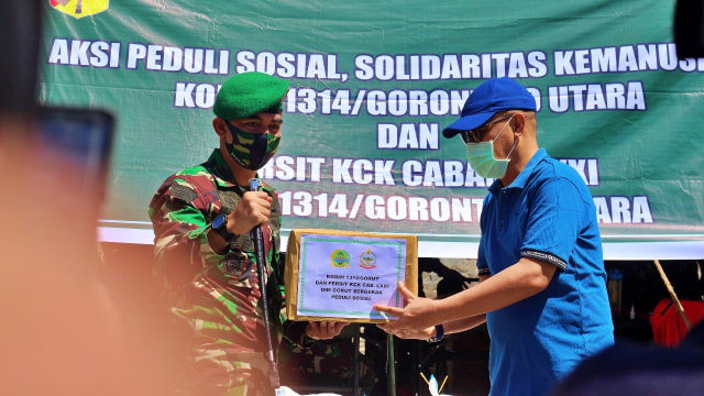 Dandim 1314 Gorontalo Utara (Gorut), Firstya Andrean Gitrias, menyerahkan bantuan kepada Kepala Dinas Sosial Kota Gorontalo, Nikson Rahman. Senin, (6/7). Foto: Dok banthayoid (Wawan Akuba)