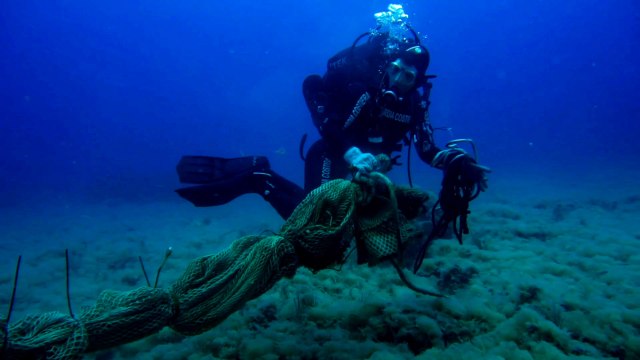 Penyelam dari Penjaga Pantai Italia mengumpulkan jaring ikan yang ditinggalkan dari dasar laut di lepas pantai Lazio selama penelitian. Foto: ITALIAN COAST GUARD via Reuters