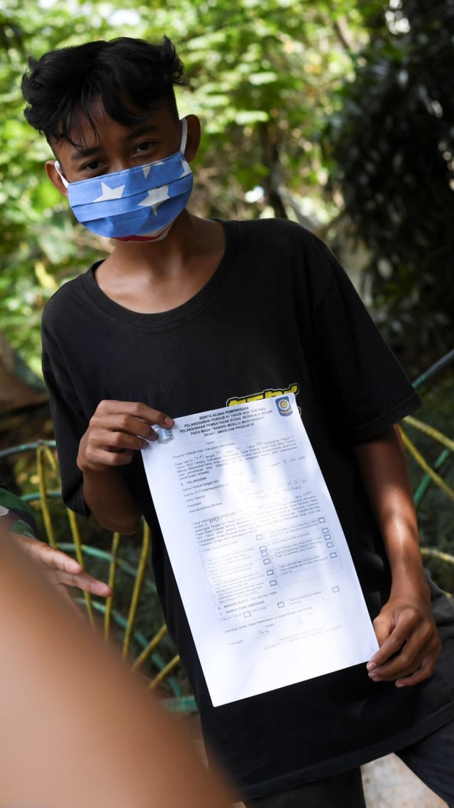 Seorang warga dengan membawa surat bukti pelanggaran karena tidak mengenakan masker di Jakarta, Selasa (7/7). Foto: Wahyu Putro A/Antara Foto