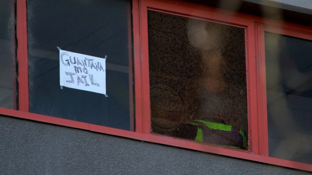 Seorang petugas polisi berpatroli didekat tulisan "Penjara Guantanamo" di sebuah apartemen di Melbourne, Australia, 8 Juli 2020. Foto: Sandra Sanders/REUTERS