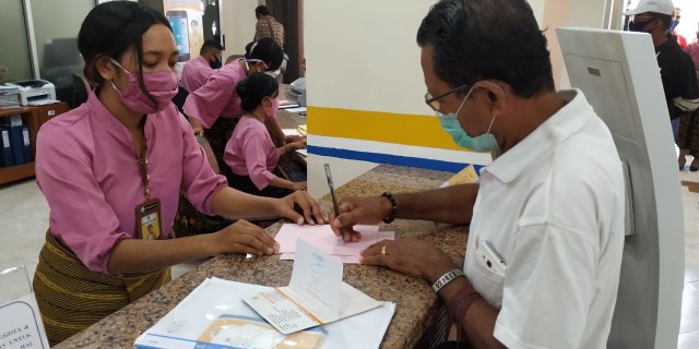 Salah seorang anggota KSP Kopdit Obor Mas mendatangi kasir untuk mengurus pembagian dividen anggota di Kantor pusat KSP Kopdit Obor Mas, Kamis (9/7/2020). Foto: Mario WP Sina.